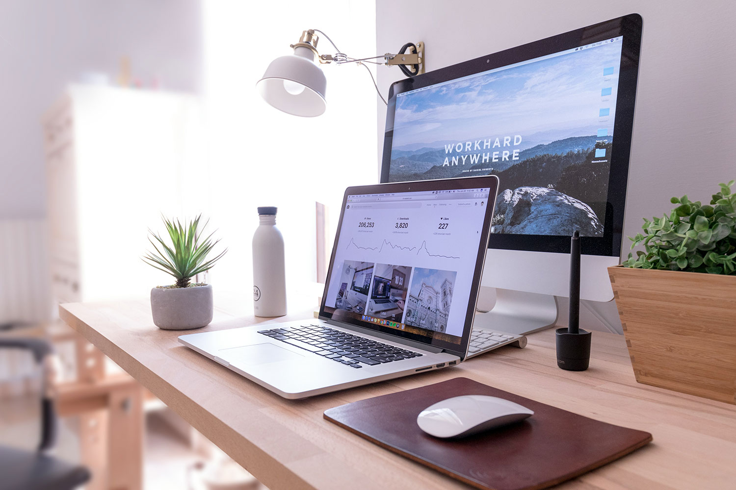 Desk with a laptop and second monitor. Second monitor has "Work hard anywhere" showing