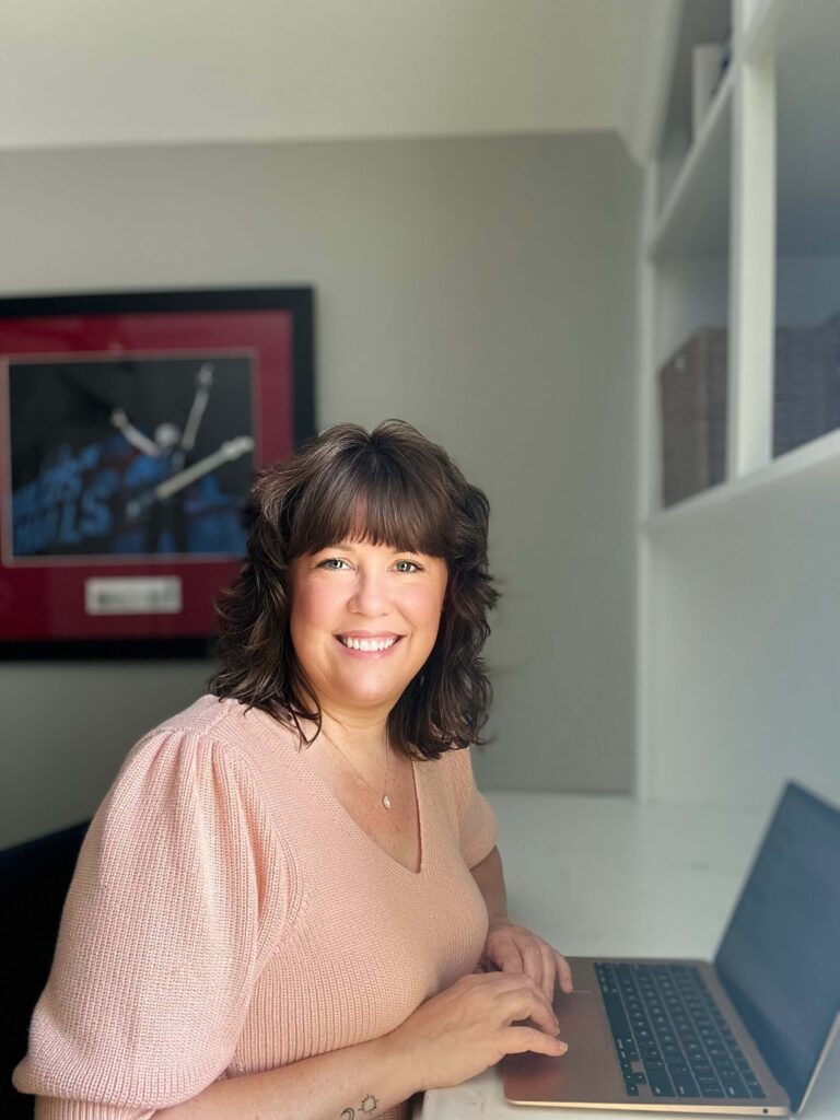 Lindsey Parker sitting at her desk smiling at the camera. Computer monitor in the background.