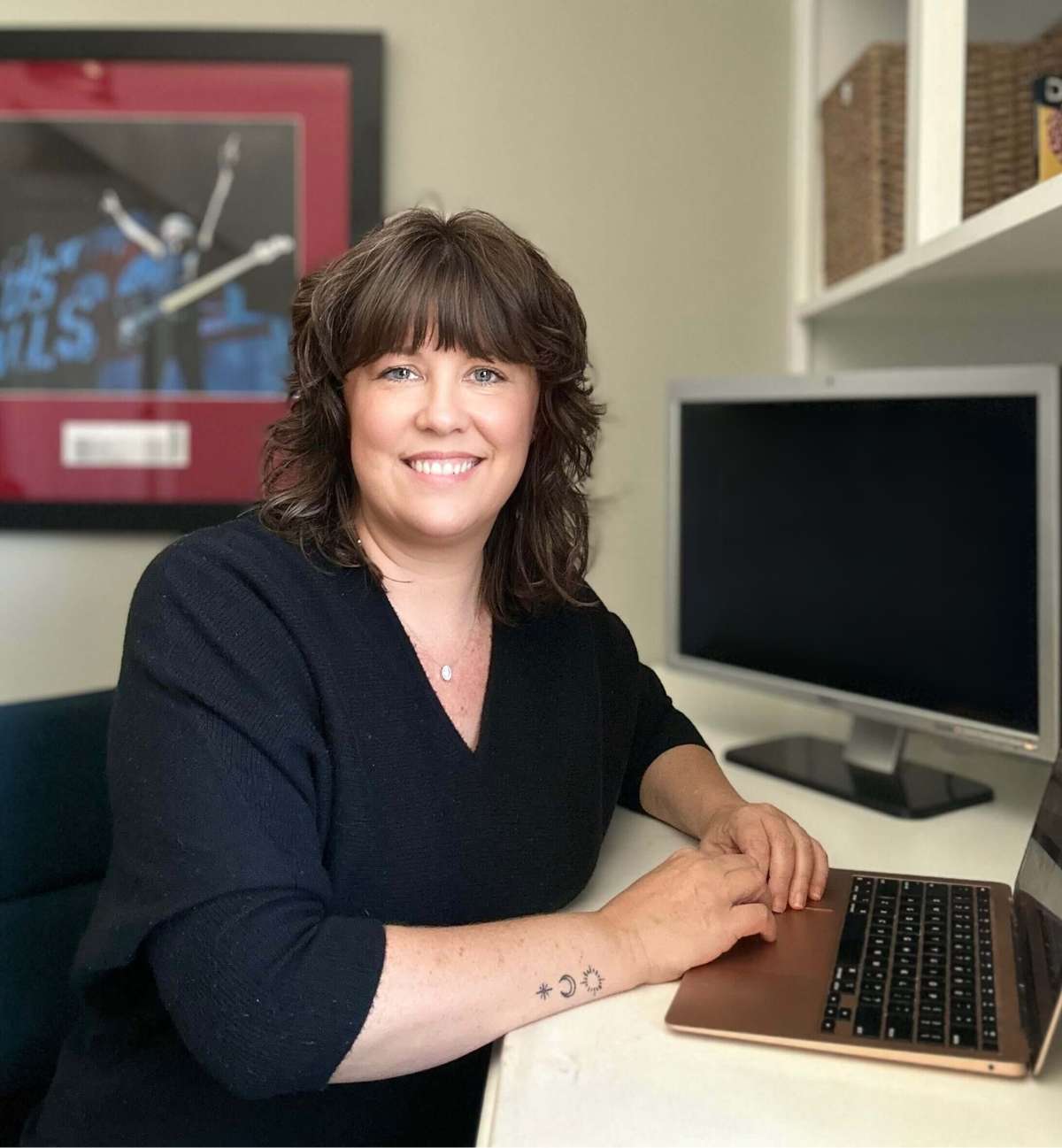 Lindsey Parker sitting at her desk smiling at the camera. Computer monitor in the background.